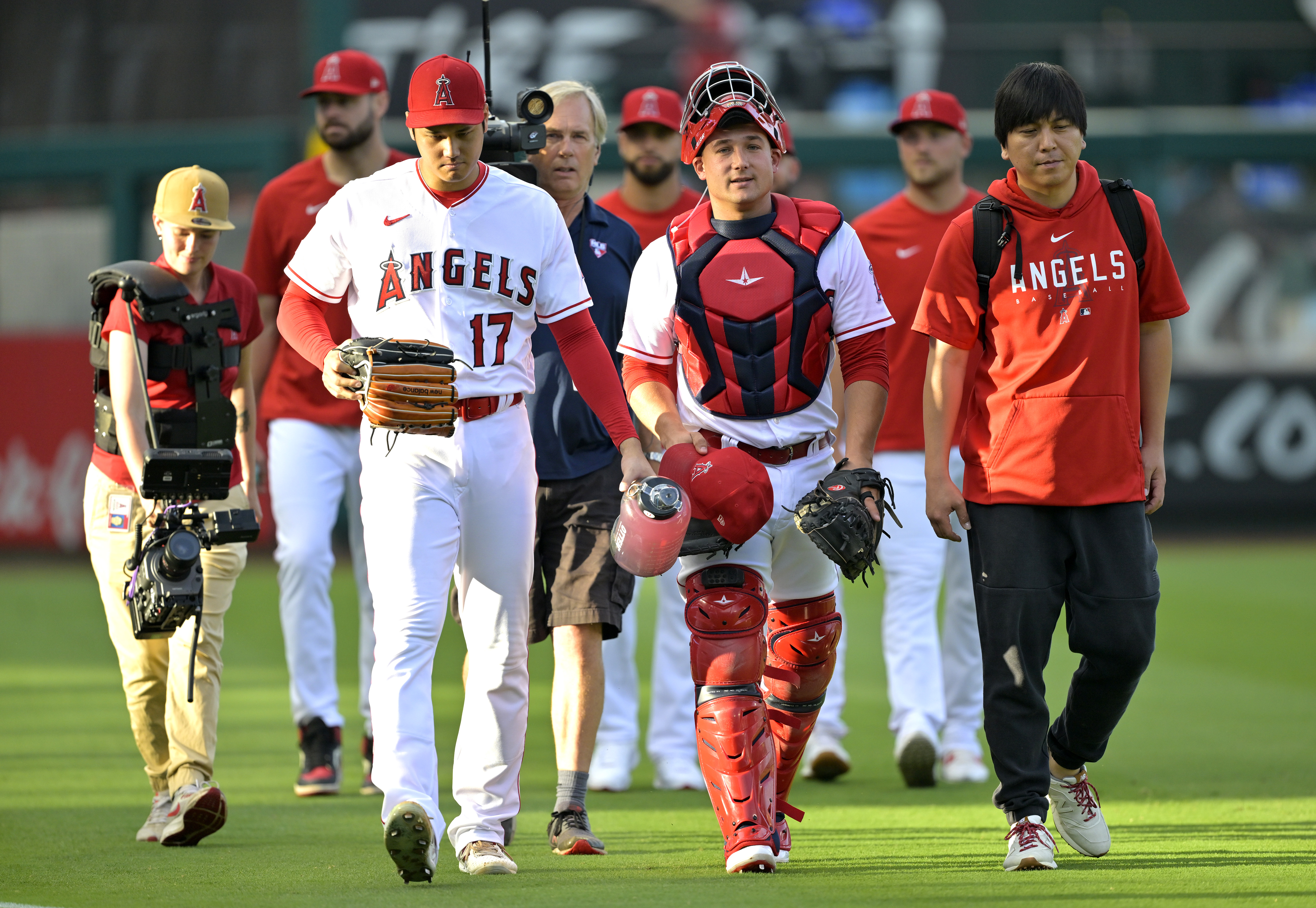 Shohei Ohtani and Matt Thaiss of the Los Angeles Angels talk with Ippei Mizuhara as they walk in from the bullpen.