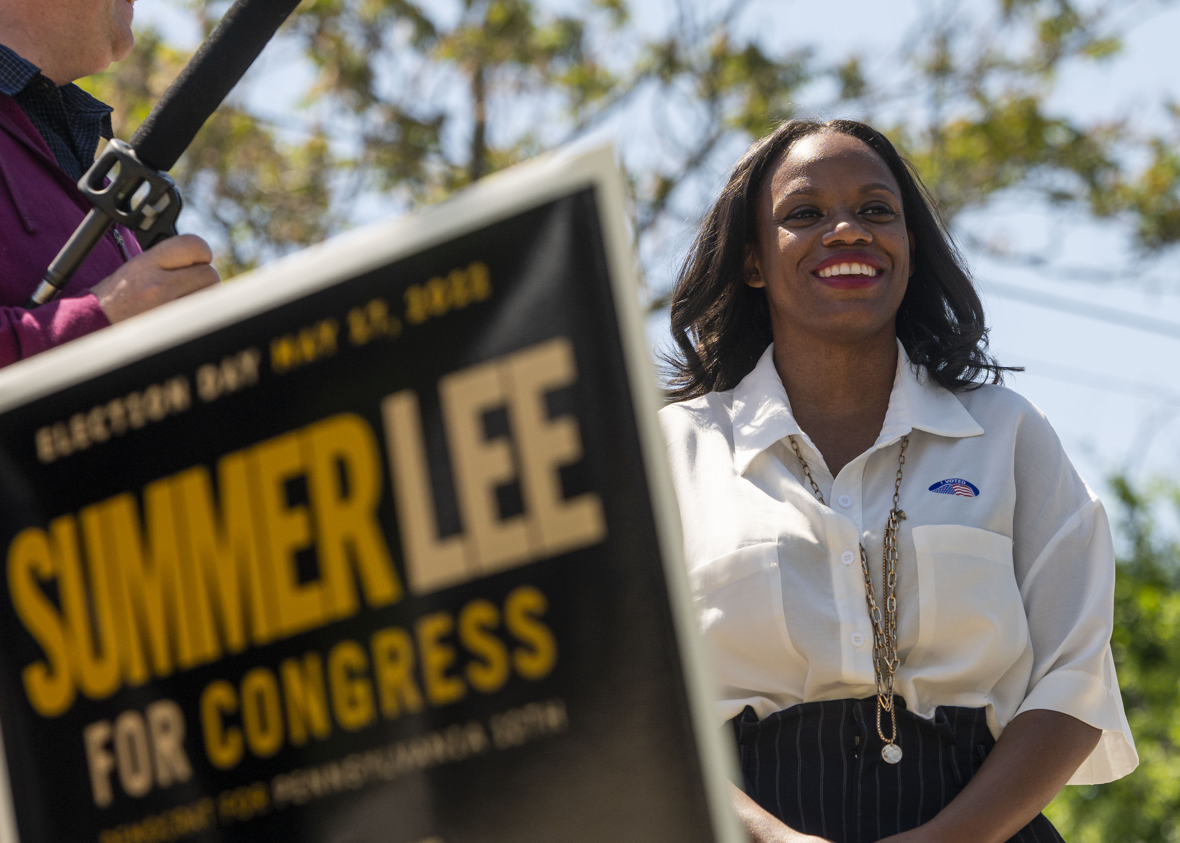 Summer Lee smiling outside beside a sign that reads “Summer Lee for Congress.”