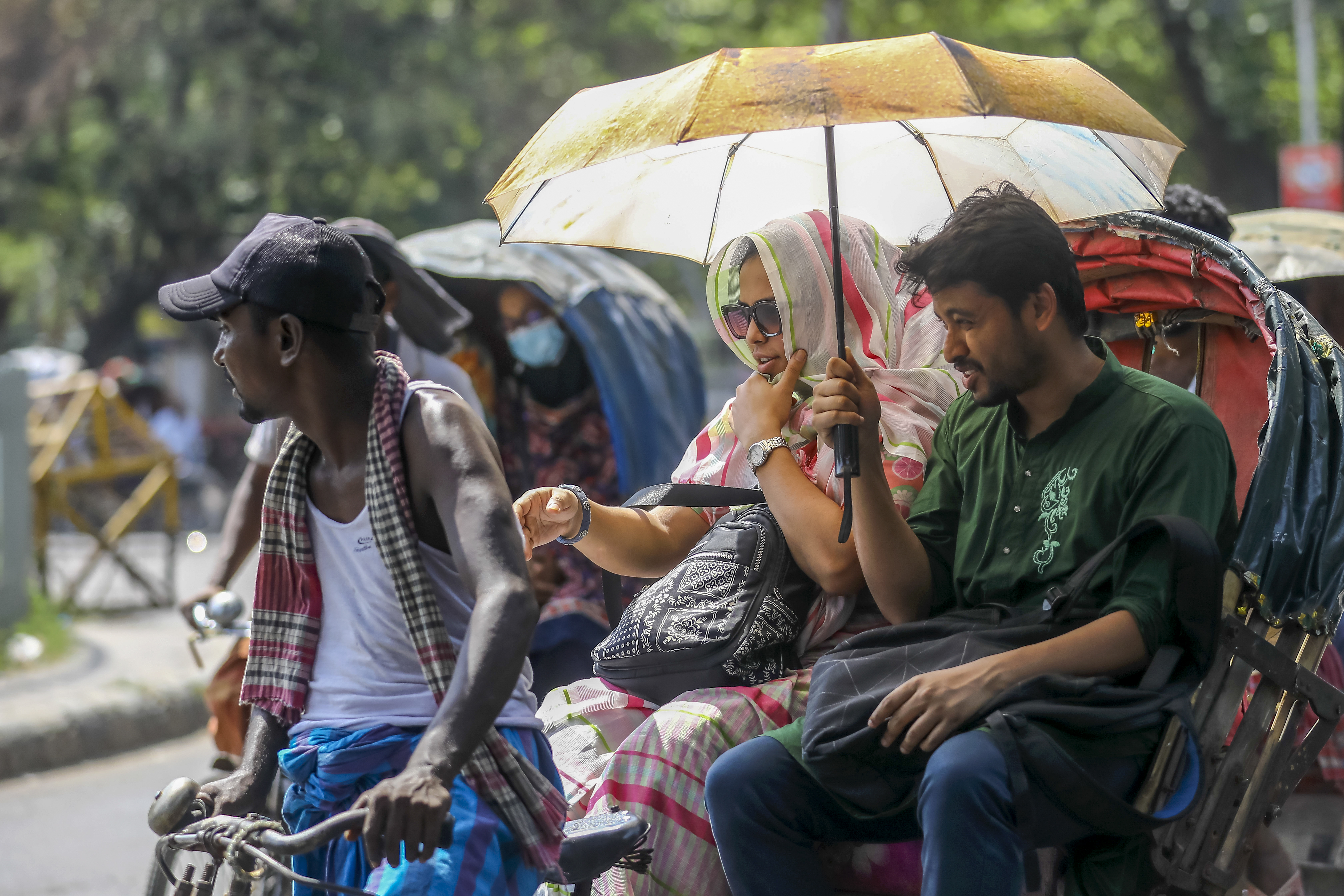 Rickshaw pullers are standing with umbrellas and caps on to get shade from the sun during the countrywide heat wave in Dhaka, Bangladesh, on April 29, 2024.