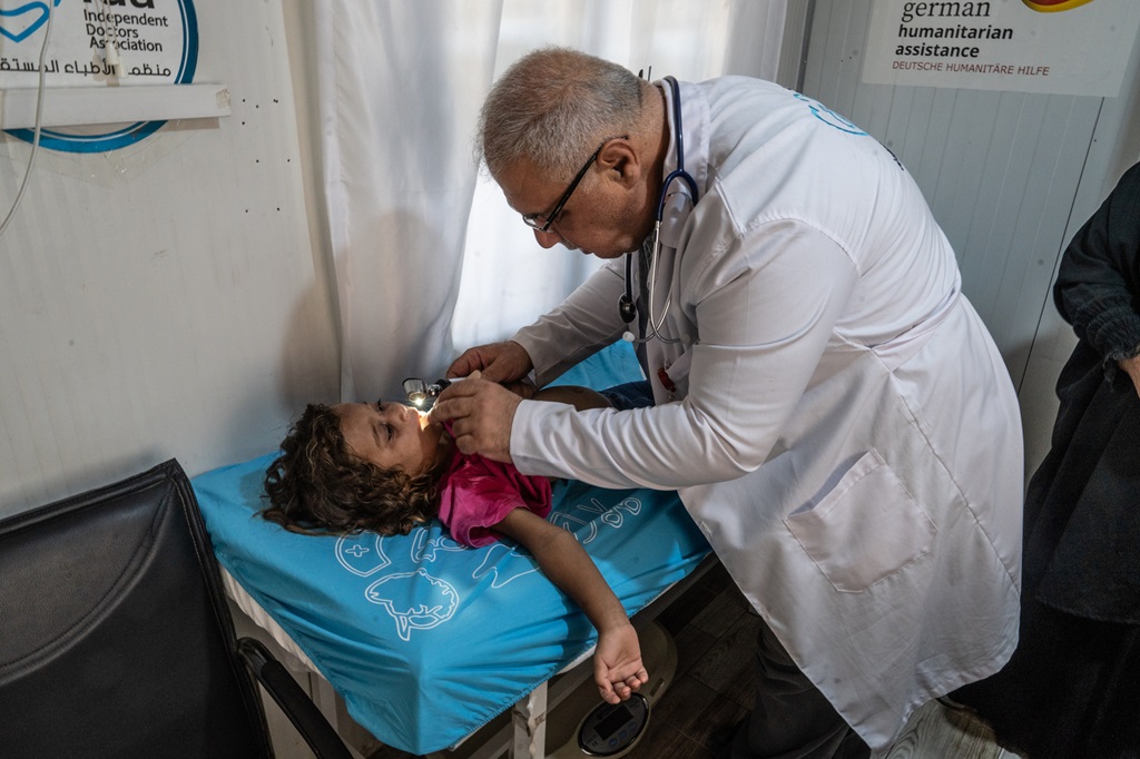 At the Shamarekh Primary Health Center in Azzaz, Abdel Ghani Shehab El Deebo, a nurse from the Independent Doctors Association (IDA) examines 5-year-old Alaa who resides at the nearby IDP camp with her family.