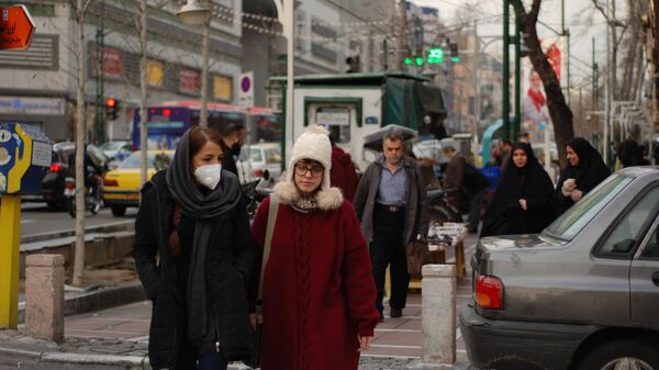 Люди в медицинских масках на улице столицы Ирана города Тегеран