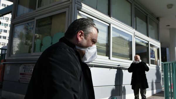 Люди, одетые в защитные маски, около больницы AHEPA, где проходит лечение первый пациент с подтвержденным   коронавирусом, в Салониках, Греция