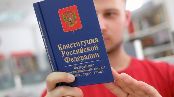 Молодой человек держит Конституцию РФ