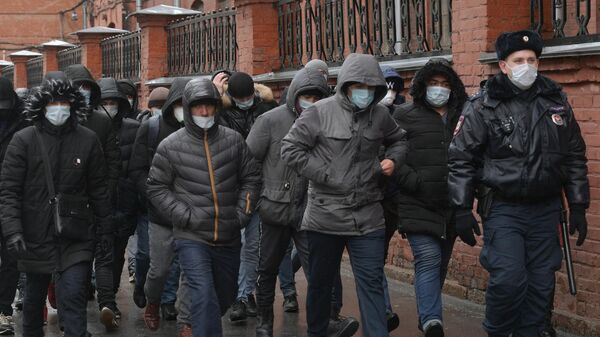 Сотрудник полиции выстраивает в очередь мигрантов у здания УФМС в Санкт-Петербурге