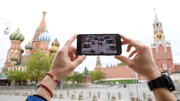 Молодой человек смотрит трансляцию акции Бессмертный полк на Красной площади в Москве