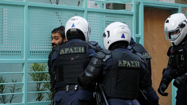  Сотрудники полиции задерживают участника акции протеста в Афинах, Греция, 6 декабря 2020