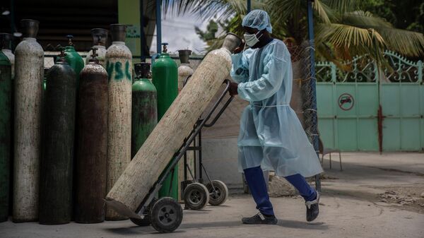 Сотрудник больницы перевозит кислородные баллоны в Порт-о-Пренсе, Гаити