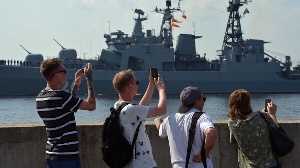 Люди на набережной наблюдают за подготовкой кораблей ВМФ РФ к параду в Кронштадте