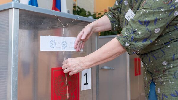 Сотрудник участковой избирательной комиссии №51 в городе Петропавловске-Камчатском пломбирует стационарные урны для голосования
