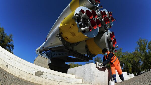 Рабочий приводит в порядок постамент памятника с макетом ракеты-носителя Союз в городе Байконур