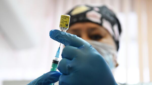 Медицинская сестра набирает в шприц вакцину Спутник
