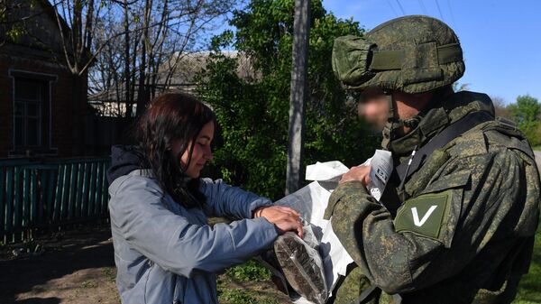 Военнослужащий ВС РФ раздает российскую гуманитарную помощь жителям одного из сел в Харьковской области