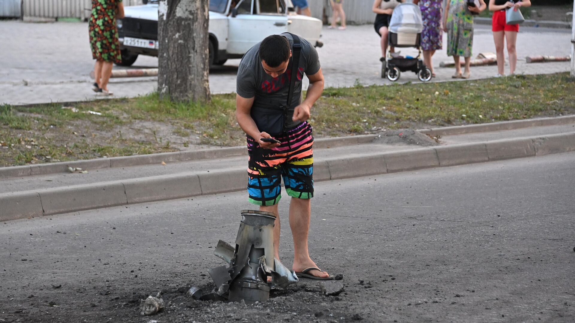 Жители города около неразорвавшегося боеприпаса на месте обстрела Ленинского района Донецка - РИА Новости, 1920, 18.08.2022