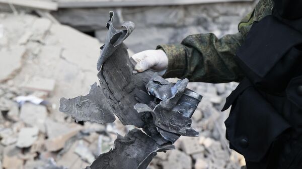 Следователь демонстрирует часть снаряда на месте пострадавшего в результате обстрела со стороны ВСУ здания. Архивное фото