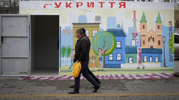 Люди проходят мимо бетонного навеса с надписью укрытие в украинском городе