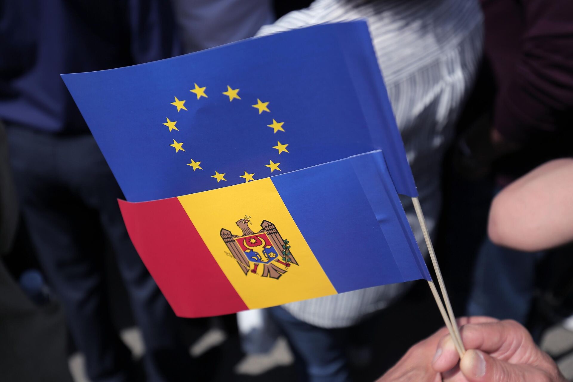 Флаги Молдавии и Евросоюза в руках одного из участников митинга на площади Великого Национального Собрания в Кишиневе - РИА Новости, 1920, 07.03.2024