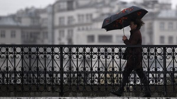 Мужчина под зонтом на одной из улиц в центре Москвы
