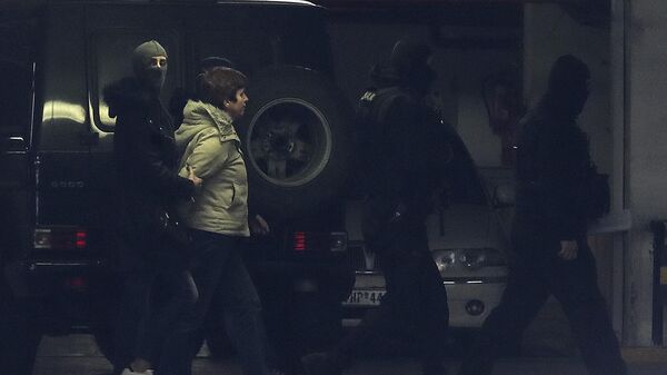 Офицеры антитеррористической службы ведут Полу Рупу в прокуратуру в Афинах
