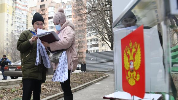 Член избирательной комиссии оформляет документы жительнице города на выездном голосовании в Донецке в первый день досрочного голосования на выборах президента РФ в Донецкой народной республике