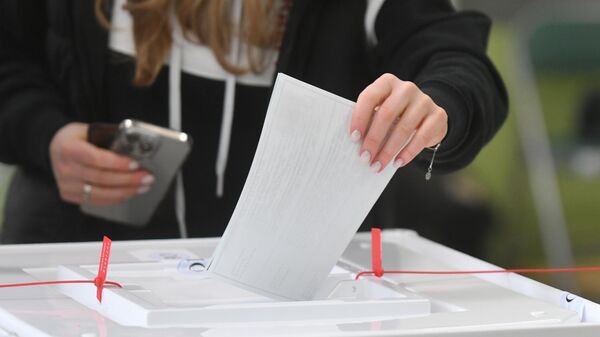 Девушка голосует на выборах президента России на избирательном участке 
