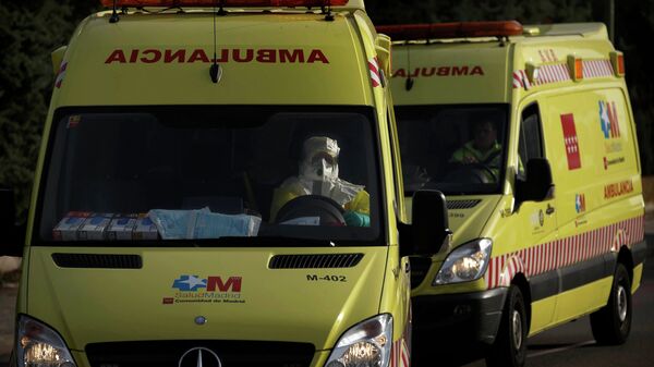Водитель скорой помощи в защитном костюме везет пациента в больницу в Мадриде
