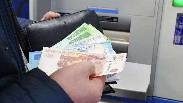 Женщина снимает деньги в банкомате