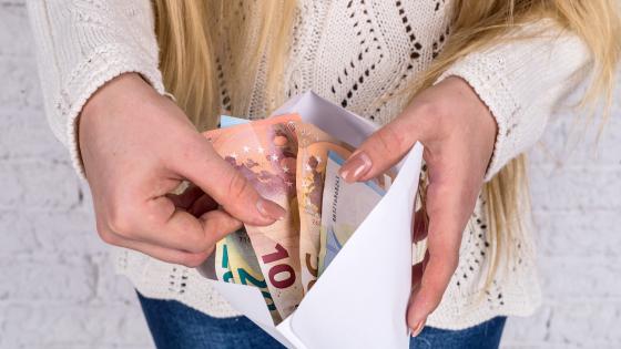 Woman receiving wages in cash in envelope