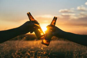 Two bottles clicking together in front of sunset