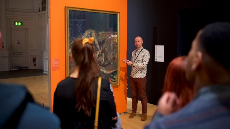 Jon Sleigh giving a talk in front of Francis Bacon's 'Figures in a Landscape'