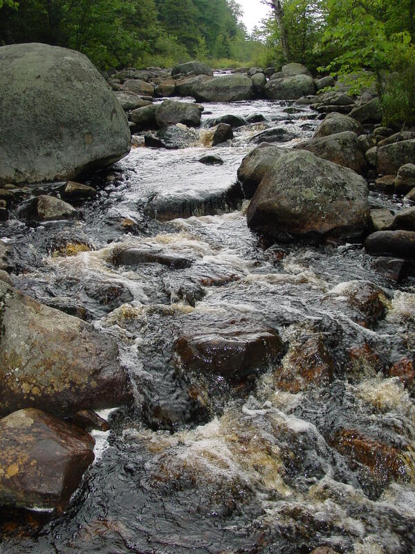 stream of fast moving water running over rocks and boulders