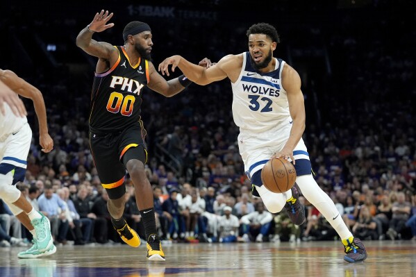 Minnesota Timberwolves center Karl-Anthony Towns (32) drives on Phoenix Suns forward Royce O'Neale during the first half of Game 3 of an NBA basketball first-round playoff series, Friday, April 26, 2024, in Phoenix. (AP Photo/Matt York)