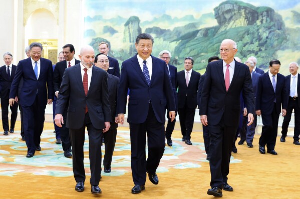 In this photo released by Xinhua News Agency, Chinese President Xi Jinping, center, walks with representatives from American business, strategic and academic communities at the Great Hall of the People in Beijing, March 27, 2024. (Huang Jingwen/Xinhua via AP)