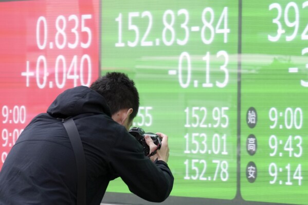 A photographer takes photos of an electronic board showing Japan's yen and U.S. dollar exchange rate at a securities firm Thursday, April 11, 2024, in Tokyo. (AP Photo/Eugene Hoshiko)