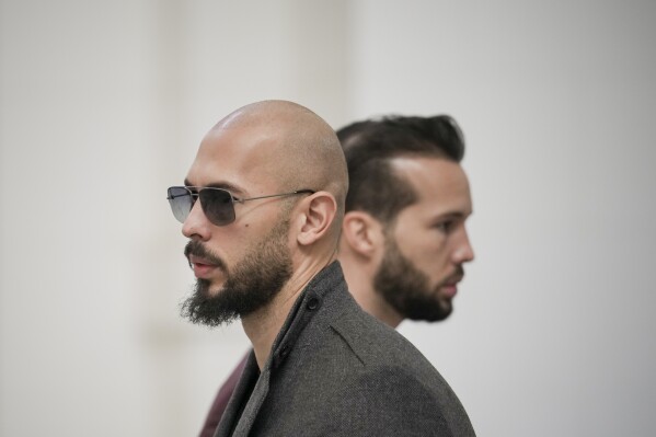 FILE - Andrew Tate, left, and his brother Tristan, right, wait inside the Court of Appeals building in Bucharest, Romania, Tuesday, Jan. 30, 2024. A court in Romania's capital on Friday, April 26, 2024, ruled that a trial can start in the case of influencer Andrew Tate, who is charged with human trafficking, rape and forming a criminal gang to sexually exploit women.(AP Photo/Vadim Ghirda, File)