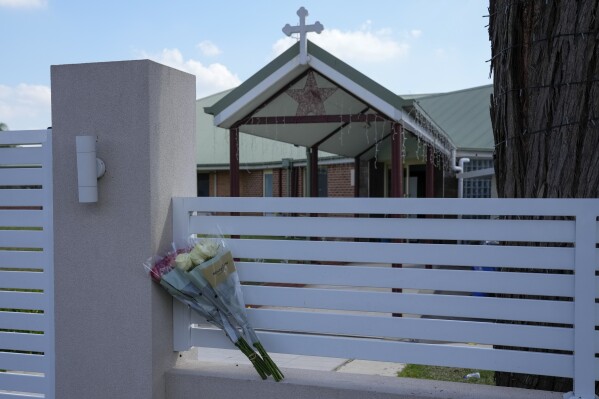 Flores sit on a fence outside the Christ the Good Shepherd church in suburban Wakely in western Sydney, Australia, Tuesday, April 16, 2024. A man has been arrested after reportedly stabbing a Christian bishop and multiple churchgoers during a televised service in Sydney Monday, April 15, 2024, police said. There were no reports of life-threatening injuries. (AP Photo/Mark Baker)