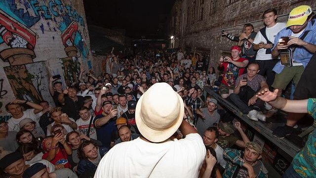 a musician performs to a group on a crowded street