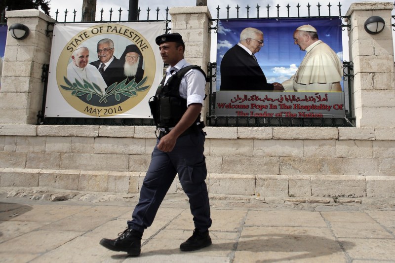 A Palestinian policeman stands guard near a banner bearing portrait of Pope Francis and Palestinian Authority President Mahmud Abbas displayed in the Church of Nativity, in the West Bank city of Bethlehem, on May 19, 2014.