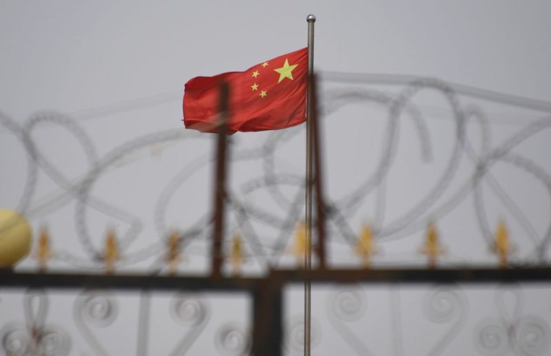 A Chinese flag flies behind razor wire