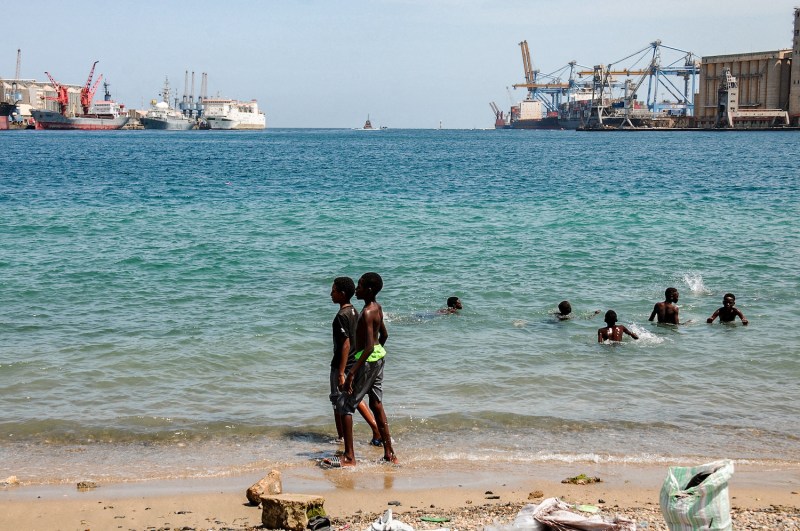 Children swim in the water near docked ships at Port Sudan.