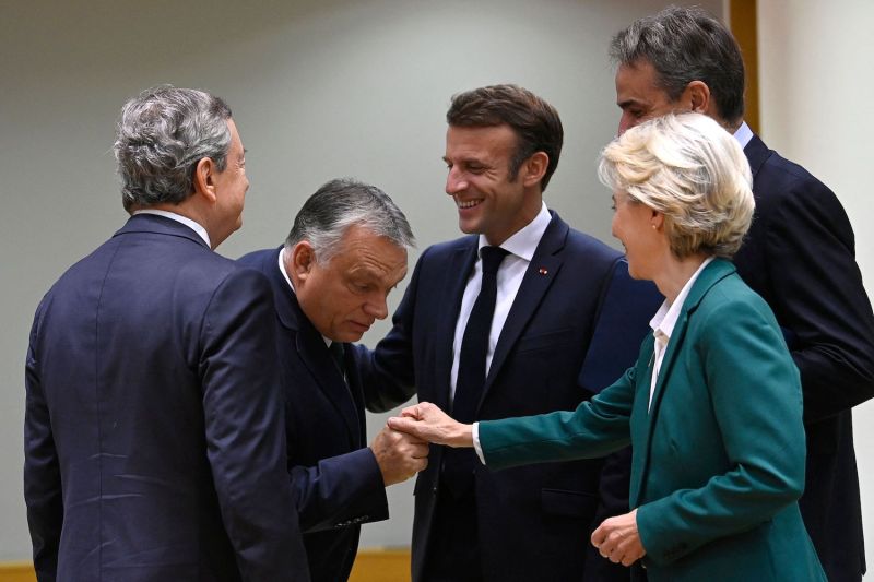 Hungarian Prime Minister Viktor Orban shakes hands with European Commission President Ursula von der Leyen as then-Italian Prime Minister Mario Draghi (L), French President Emmanuel Macron (C), and Greek Prime Minister Kyriakos Mitsotakis (R) look on during the second day of an EU leaders summit at the European Council building in Brussels.