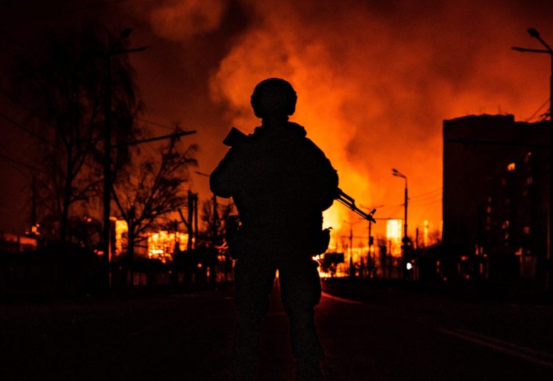A Ukrainian special forces soldier stands in front of a burning gas station after Russian attacks in Kharkiv, Ukraine, on March 30, 2022.