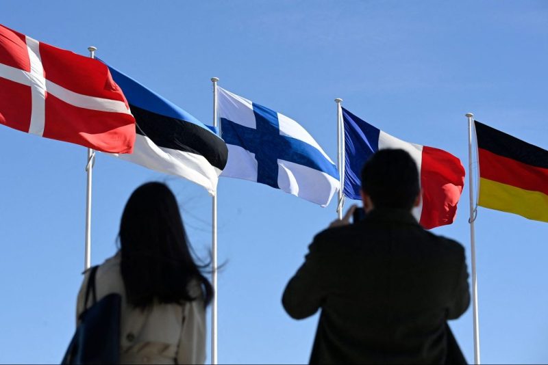 People stand after the ceremonial raising of the Finnish national flag at NATO headquarters in Brussels on April 4.