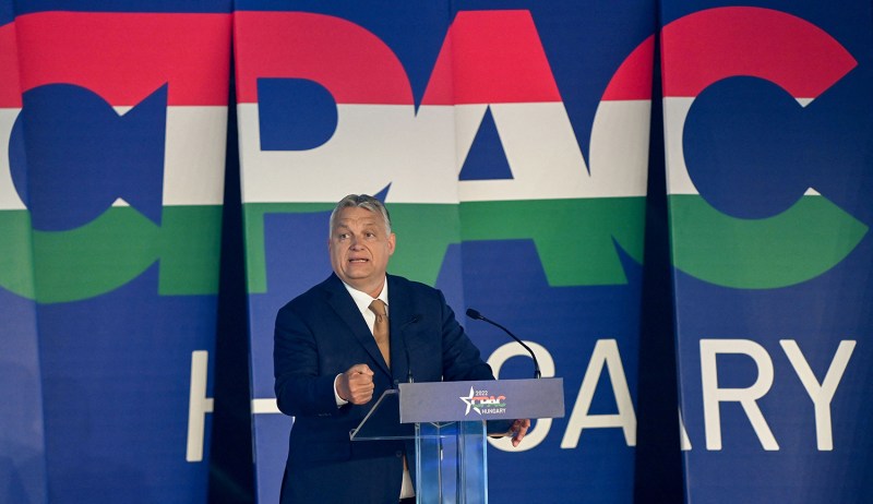 Hungarian Prime Minister Viktor Orban stands behind a podium in front of a sign that says "CPAC Hungary" during a conference session in Budapest.