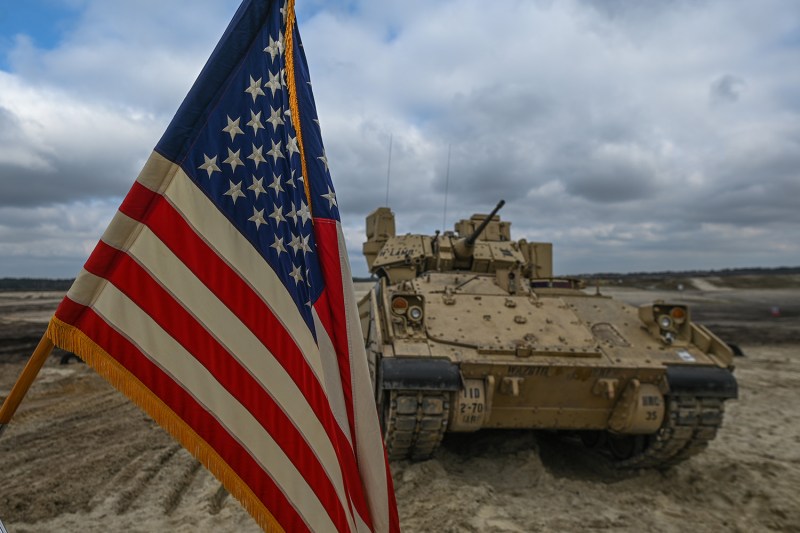 A U.S. Bradley Fighting Vehicle is seen behind a U.S. flag during during a training session by U.S. soldiers in Nowa Deba, Poland.