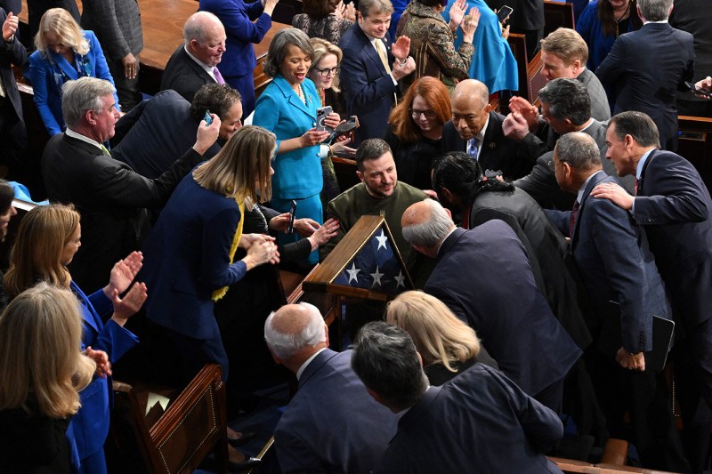 Ukraine's President Volodymyr Zelensky is surrounded by by members of Congress as he carries a U.S. flag in a triangular box following his address at the Capitol in Washington on Dec. 21, 2022.