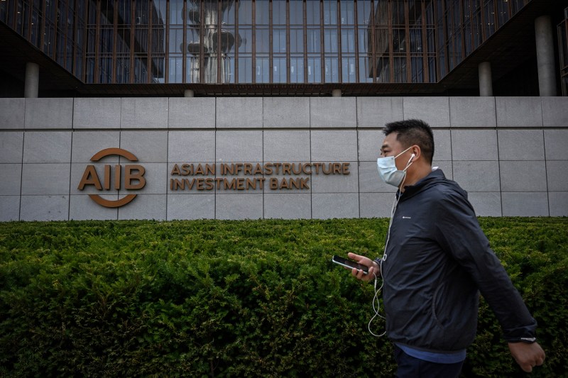 A man walks past the logo of the Asian Infrastructure Investment Bank at its headquarters in Beijing on June 15. Jade Gao/AFP via Getty Images