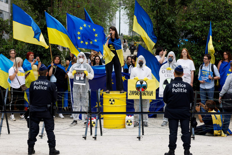 A woman holding a Ukrainian flag speaks during a pro-Ukraine rally in Brussels.