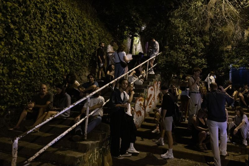 People sit on stairs outside a popular bar at night in Istanbul, Turkey.