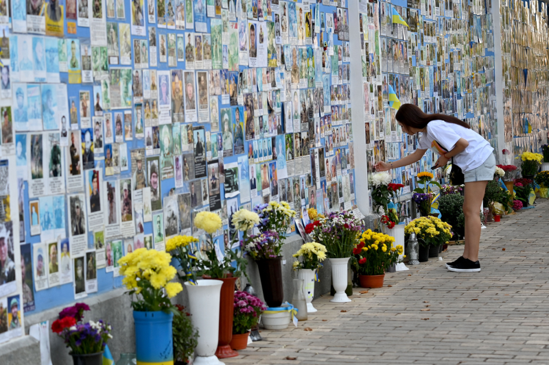 A girl touches a photograph of her relative on the Memory Wall of Fallen Defenders of Ukraine in the Russian-Ukrainian war in Kyiv.