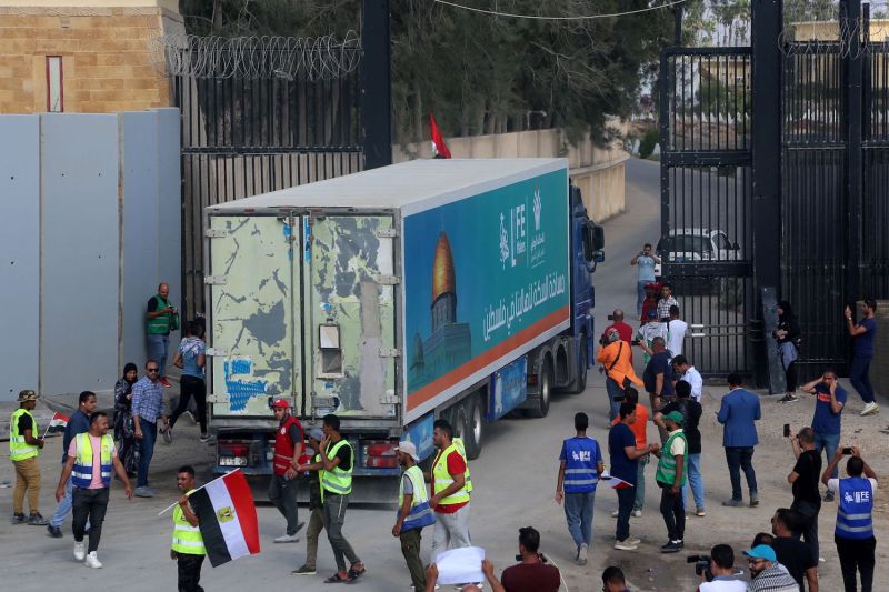 People watch humanitarian aid enter Gaza through the Rafah Border Crossing.